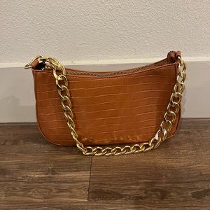 Burnt orange alligator shoulder purse with gold chain strap.